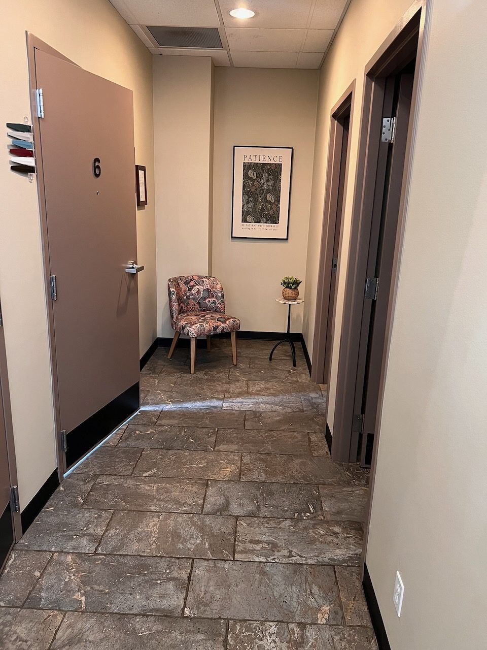 The end of a hallway outside exam room 6, with an upholstered chair and a small plant