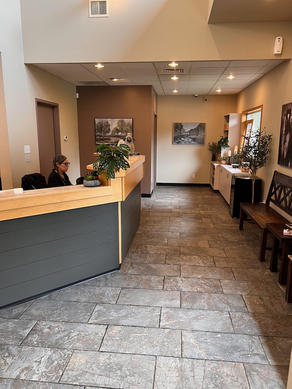 The reception counter and waiting area, with a bench along the wall and landscape prints overhead